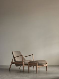 a chair and foot stool sitting next to each other in front of a white wall