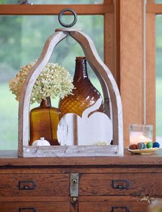 vases and other items are displayed on a chest in front of a window with wooden shutters