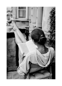 a woman sitting in a chair reading a book