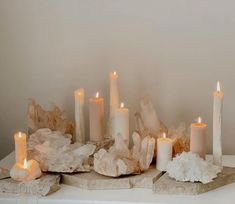 some white candles sitting on top of rocks with crystals in front of the candle holders