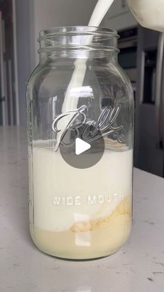 a glass jar filled with liquid sitting on top of a counter next to a spoon