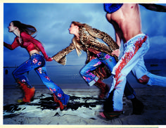 three women are dancing on the beach with their feet in the air and one woman is holding her leg