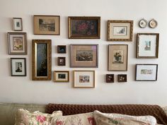 a living room filled with lots of framed pictures on the wall next to a couch