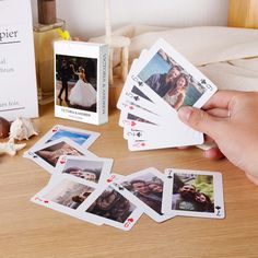 a person is holding playing cards with pictures on them next to a card game box