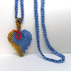 a blue beaded necklace with a heart shaped pendant hanging from it's side