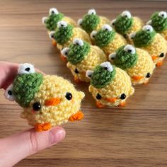 small crocheted birds are being held up by someone's hand on a table