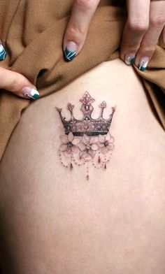 a woman's stomach with a crown tattoo on her belly and hands behind her