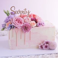 there is a cake with flowers on it and the word seventy spelled in gold letters