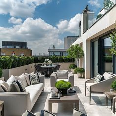 an outdoor living area with couches, tables and potted plants on the roof