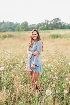 a beautiful young woman standing in the middle of a field