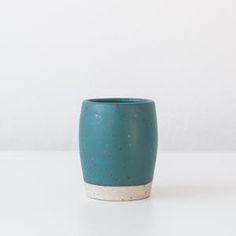 a teal and white vase sitting on top of a table next to a wall