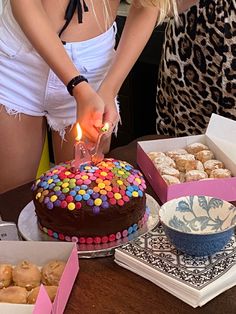 a woman lighting a candle on top of a chocolate cake with sprinkles