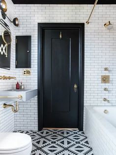 a black and white tiled bathroom with gold hardware on the door, toilet and bathtub