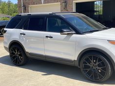 a white suv parked in front of a house with black rims and tires on it