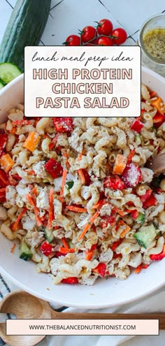 a white bowl filled with pasta and veggies on top of a table next to a wooden spoon