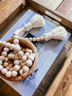 a wooden bowl filled with white beads and tassels on top of a table