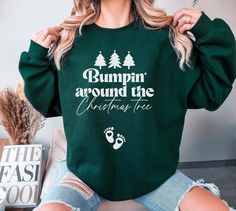 a woman wearing a green sweatshirt with the words bumpin around the christmas tree on it