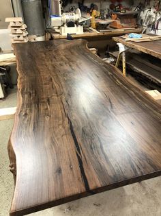 a large wooden table in a shop with lots of woodwork tools on the counter