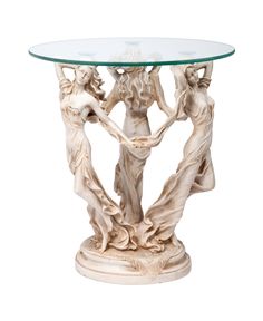 a glass topped table with statues on it's sides and a white base that has an oval glass top