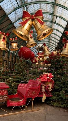 christmas trees are lined up in the middle of a building with bells hanging from them