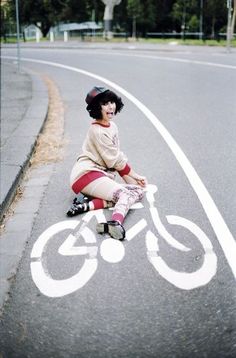 a woman sitting on the side of a road next to a bike lane