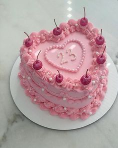 a pink heart shaped cake with cherries on top