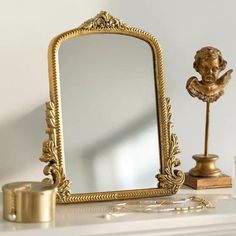 an ornate gold framed mirror sitting on top of a white mantle next to a candle