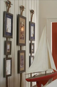 a model sailboat sitting on top of a table next to pictures and framed photos