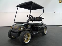 a black and yellow golf cart parked in a room with white walls on the wall