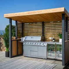 an outdoor bbq with grill, sink and table on the deck overlooking the ocean