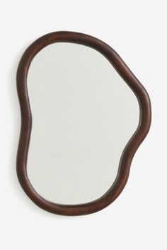 an oval wooden mirror on a white wall with a brown frame and wood trim around the edges