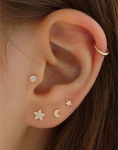 an ear with three stars and two moon piercings on it's sides, one is