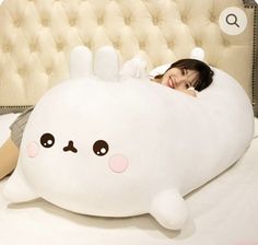 a woman laying on top of a bed with a large stuffed animal in front of her