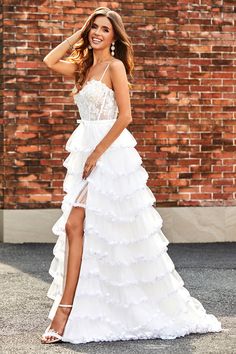 a woman wearing a white dress and high heels posing in front of a brick wall