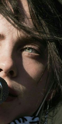 a close up of a person holding a microphone in front of her face and looking into the distance