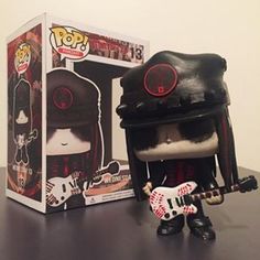 a pop vinyl figure holding a guitar in front of a box with it's cover open