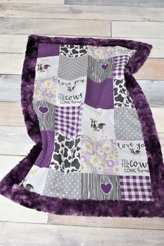 a purple and white patchwork blanket on top of a wooden floor