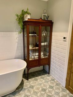 a white bath tub sitting next to a wooden cabinet