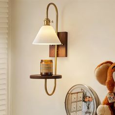 a teddy bear sitting on a shelf next to a wall light and a mirror with a candle in it