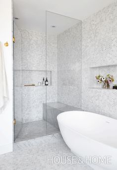 a white bathtub sitting next to a walk in shower and a glass enclosed shower stall