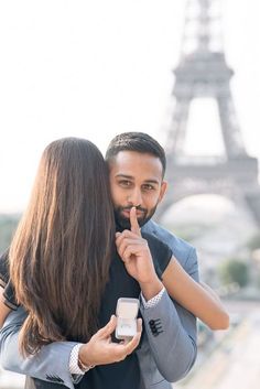 a man and woman standing next to each other in front of the eiffel tower