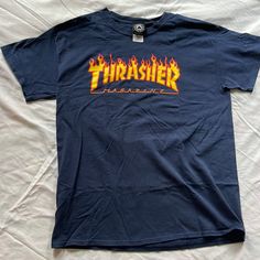 Authentic Classic Thrasher Flame Logo T-Shirt Size Men’s Large. The Iconic Thrasher Magazine Flame Logo Chest Graphic On A Dark Blue Color Way Made Of Durable Cotton Construction For A Comfortable Fit That Lasts. Never Worn/ New Without Tags Product Details Fabric Type 100% Cotton Closure Type Pull On Neck Style Crew Neck Sleeve Type Short Sleeve Blue Urban T-shirt For Fan Merchandise, Urban Blue T-shirt For Fan Merchandise, Blue Band Merch T-shirt With Logo Print, Blue Streetwear T-shirt With Back Print, Blue T-shirt With Back Print For Streetwear, Blue Logo Print T-shirt For Streetwear, Blue Streetwear Top With Back Print, Blue Band Merch Shirt For Streetwear, Blue Crew Neck Shirt With Band Merch