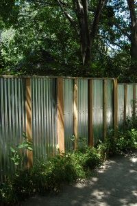 a long metal fence in the middle of a park with lots of trees around it