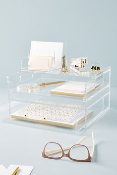 a clear desk with glasses, notebooks and other office supplies on top of it