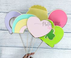 a person holding up some paper hearts with the word pretty on them in front of a white wooden background