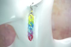 a pair of multicolored earrings hanging from a mannequin's head