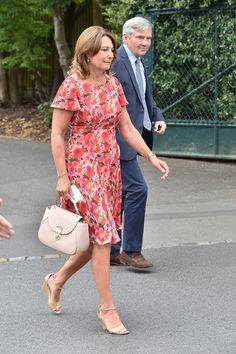 a woman in a floral dress is walking down the street with a man behind her