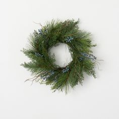 a green wreath with blue berries and pine needles