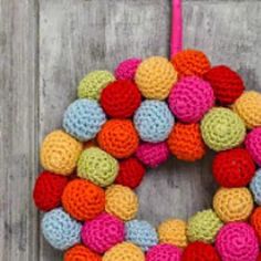 a colorful crocheted wreath hanging on a wooden door