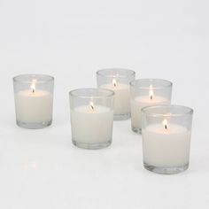 five candles are lined up next to each other on a white surface with one candle in the middle